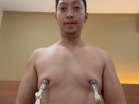 An Asian man with a thick body and white skin uses a sex toy to enhance his nipple pumps.