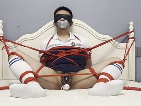 Asian man pleasuring himself with a dildo while being tied up and gagged.